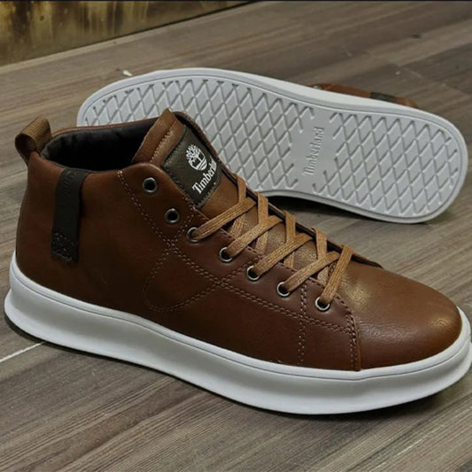 Brown leather sneaker with white sole on a wooden floor